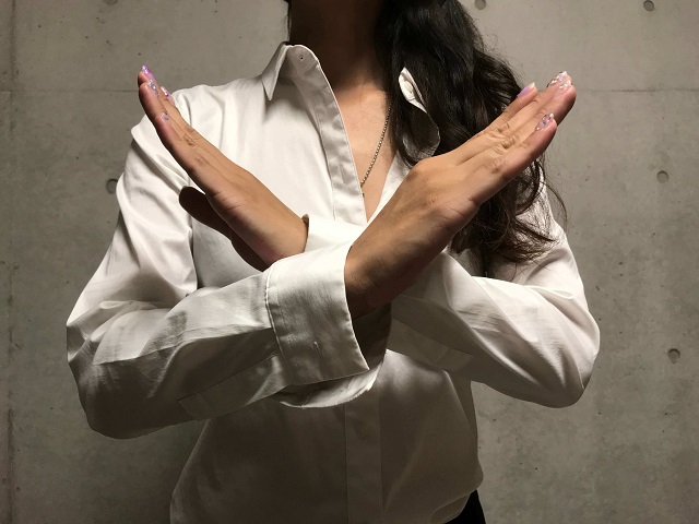両手で✕マークを作る女性